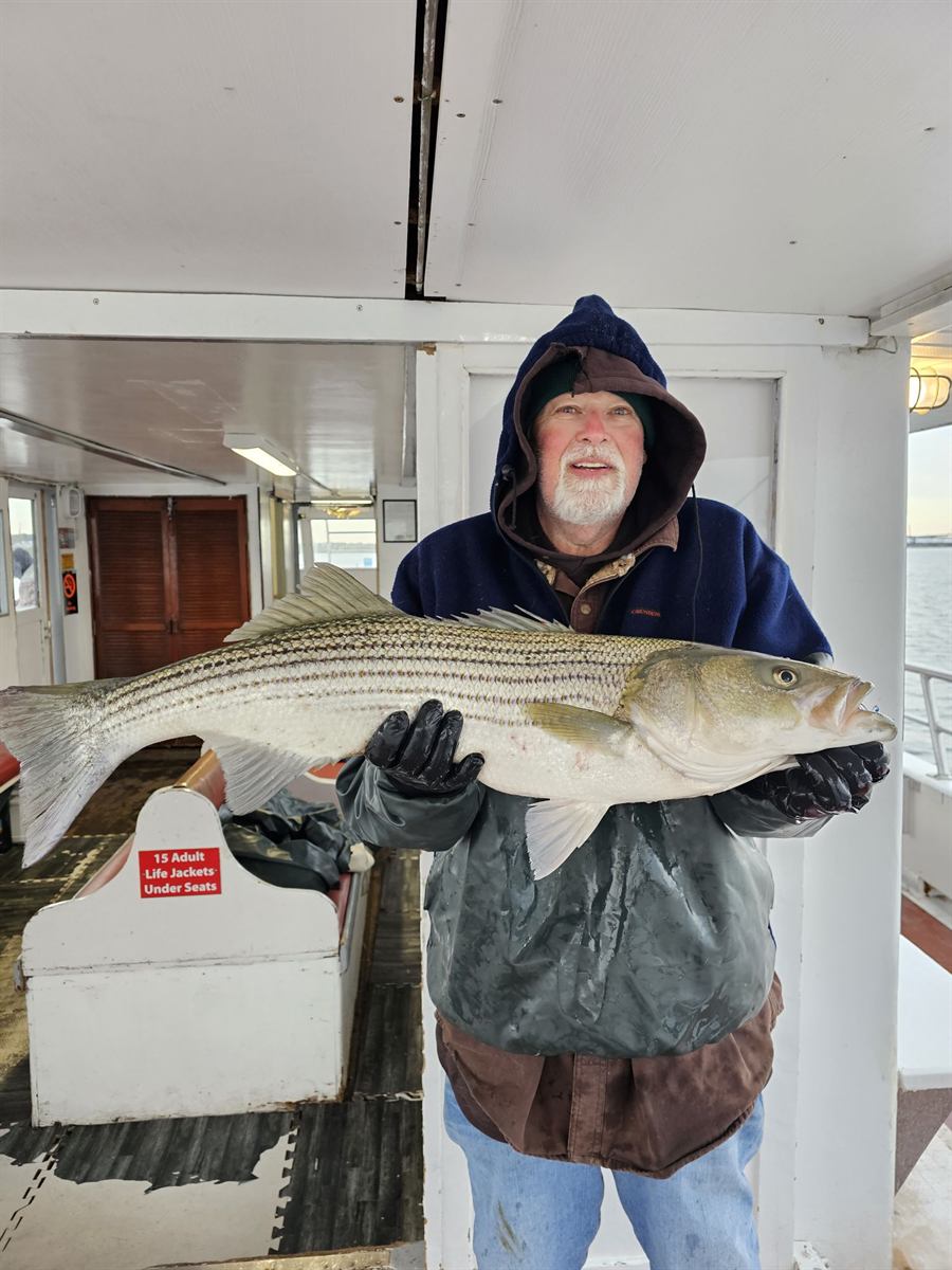 Angler in winter gear with a big striped bass